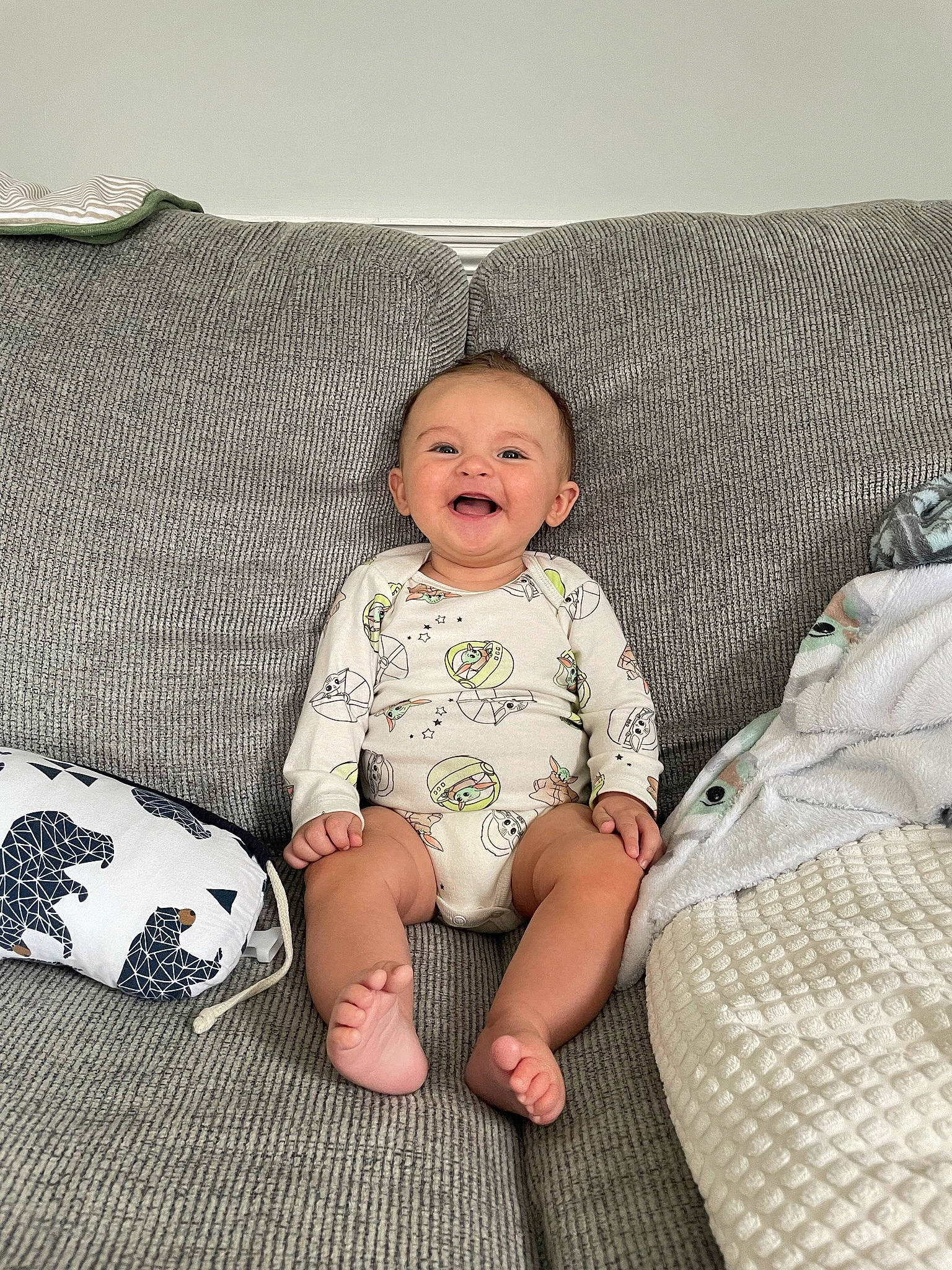 Kamden is registered to the contest to win money with this photo: baby_toddler_clothing, child, comfort, couch, eye, face, foot, grass, grey, head, human_leg, knee, linens, pattern, person, sleeve, smile, t_shirt, textile, thigh