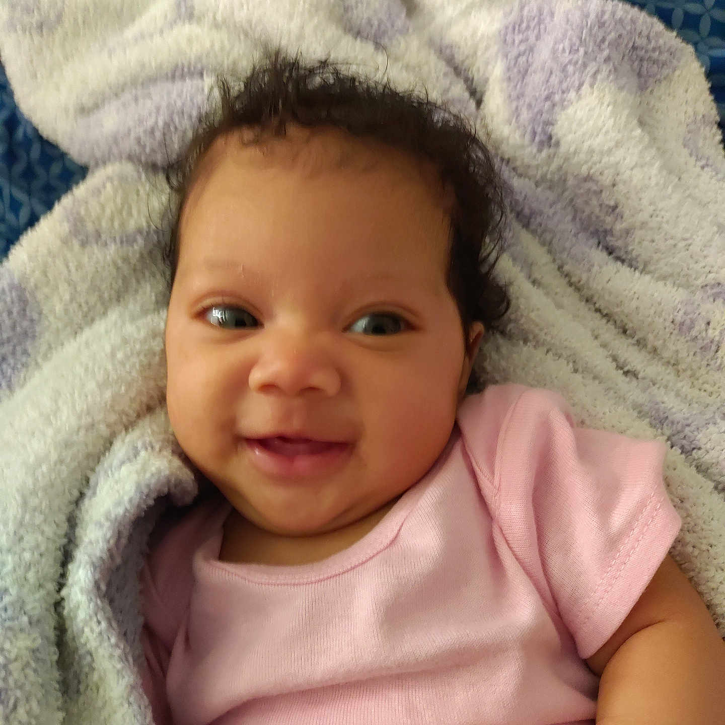 Loriena joined the competition — help win amazing prizes! baby, blanket, child, closeup, cozy, curly_hair, cute, face, happy, indoors, infant, lying_down, person, pink_clothing, portrait, skin, smile, soft_texture, towel, young_child