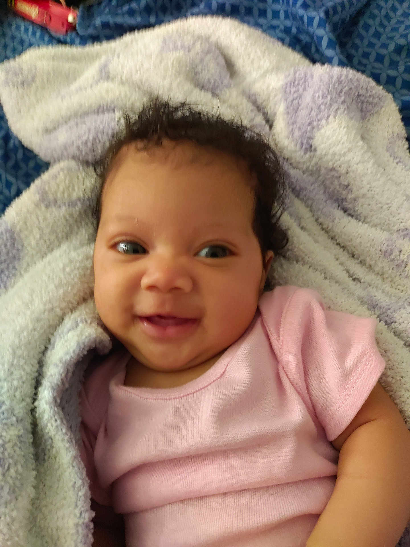 Loriena joined the competition — help win amazing prizes! baby, smile, pink_clothing, towel, curly_hair, face, infant, happy, cute, child, skin, portrait, lying_down, closeup, soft_texture, blanket, person, indoors, young_child, cozy