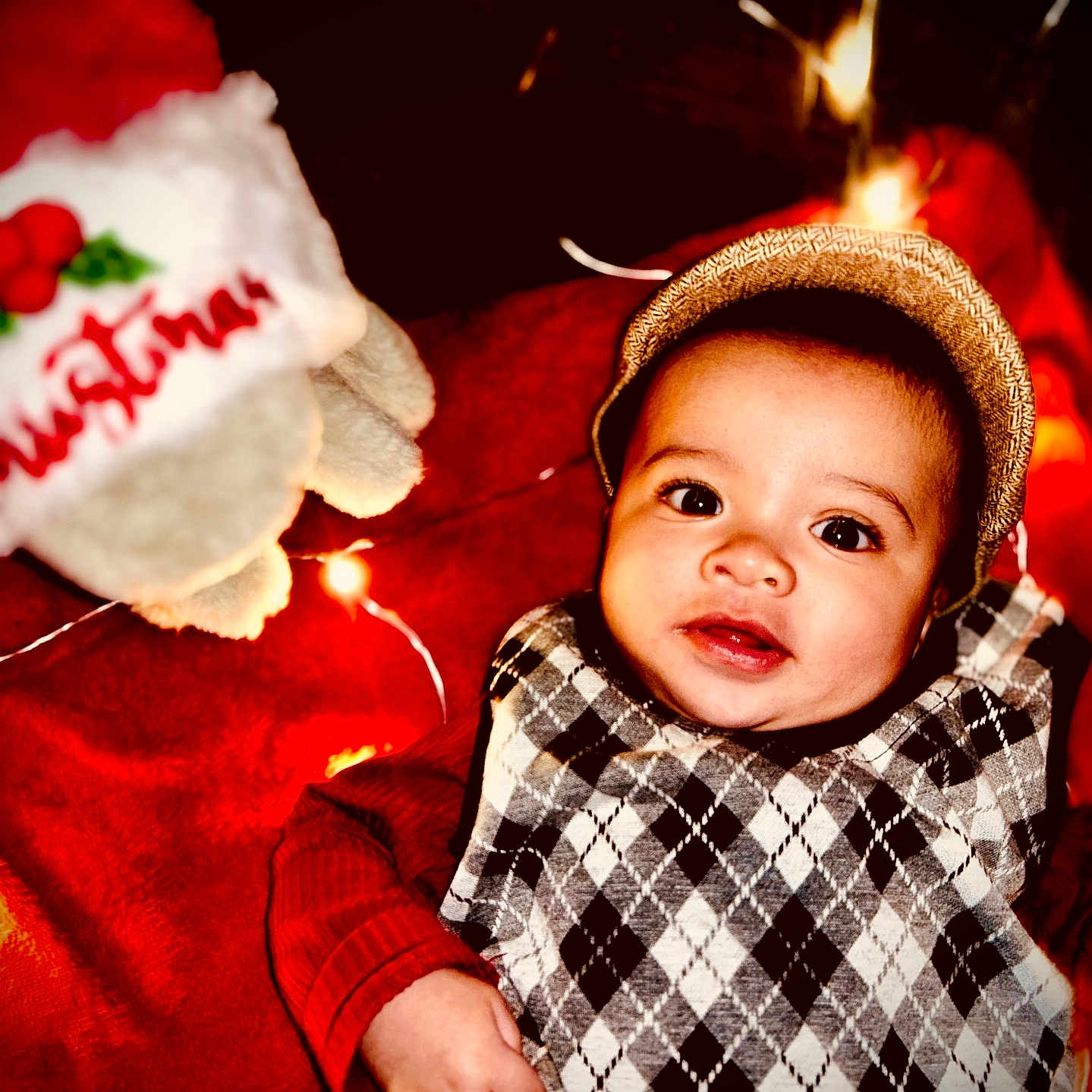 Khylae joined the competition — help win amazing prizes! argyle_sweater, baby, blanket, child, christmas, cozy, cute, decoration, face, festive, hat, holiday_lights, holiday_theme, indoors, infant, portrait, red_clothing, smiling, toy, warm_lighting