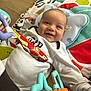Zayden is registered to the contest to win money with this photo: baby, smiling, play_mat, toy, colorful, infant, happy, child, indoors, clothing, white_outfit, face, head, hand, floor, music_notes, pillow, soft_toys, cute, lying_down