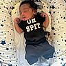 baby, infant, sleeping, clothing, black_outfit, crib, bedding, stars, hat, pacifier, cushion, pattern, newborn, child, indoors, cute, resting, striped_socks, soft, cozy