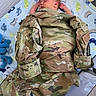 baby, newborn, sleeping, camouflage_jacket, military, blanket, dinosaur_pattern, playpen, soft_toys, infant, peaceful, cute, child, resting, indoors, portrait, cozy, small_hands, clothing, fabric
