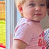 toddler, child, portrait, indoor, natural_light, pink_shirt, yellow_pants, hair_tied, window, door, backyard, grass, fence, curious, face, person, young_child, casual_clothing, cute, daylight