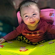 Rhaenyra joined the competition — help win amazing prizes! baby, blanket, blue_eyes, book, candid, child, clothing, face, fuzzy_toy, happy, indoor, long_sleeve, picture_book, pink_chair, portrait, reading, seat, smiling, storytime, toddler