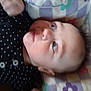 Rhaenyra is registered to the contest to win money with this photo: baby, infant, face, pillow, polka_dot, clothing, child, portrait, looking_up, cute, expression, indoor, person, young_child, head, soft, sleeping_area, pattern, fabric, closeup