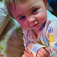 Rhaenyra is registered to the contest to win money with this photo: baby, background_blur, child, closeup, clothing, colorful, cute, expression, eyes, face, hand, indoors, infant, pajamas, person, portrait, skin, smile, soft_lighting, young