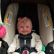 Amara joined the competition — help win amazing prizes! baby, infant, car_seat, smiling, headband, pink_bow, straps, toy, plush, strawberry, outdoor, grass, child, seatbelt, cute, clothing, happy, portrait, seat, safety