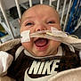 baby, infant, smiling, face, hospital, nasal_tube, blanket, clothing, nike, crib, medical, tape, happy, person, cute, closeup, healthcare, newborn, indoors, child