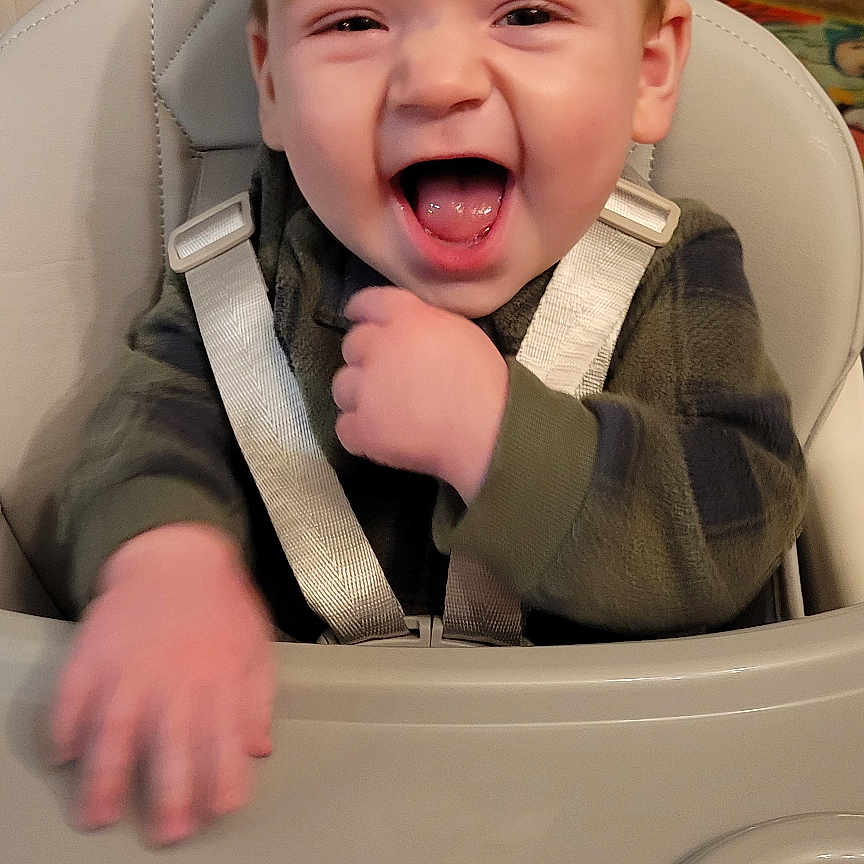 Mccoy joined the competition — help win amazing prizes! baby, carpet, child, face, floor, furniture, green_clothing, hand, happy, high_chair, indoor, laughing, living_room, mouth_open, person, seat, seat_belt, smiling, straps, toy