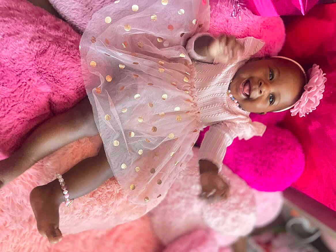 Velmarie joined the competition — help win amazing prizes! baby, girl, pink_dress, headband, flower, smiling, lying_down, plush_cushions, soft_texture, anklet, happy, child, cute, indoors, portrait, celebration, polka_dots, clothing, accessories, joy