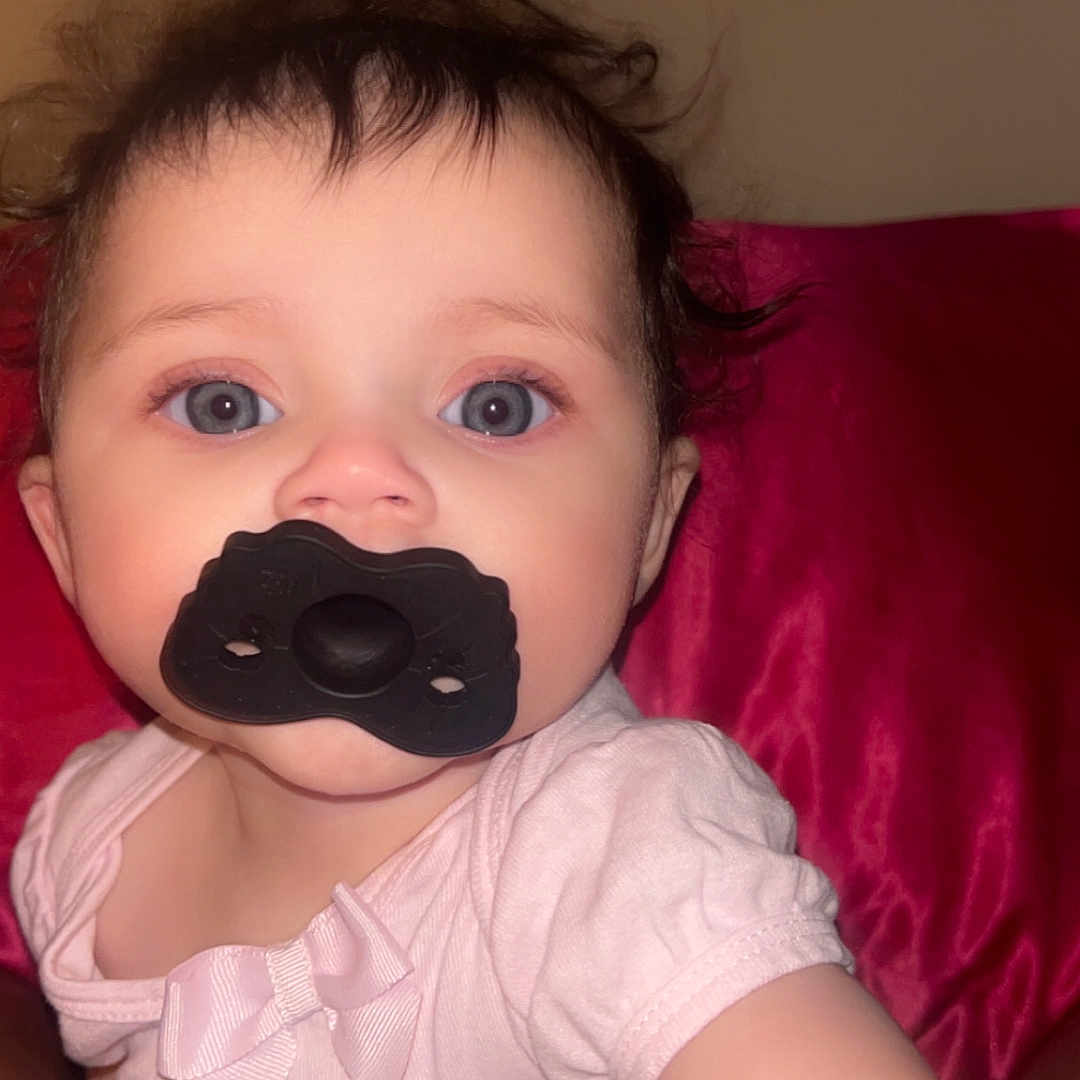 Iris is registered to the contest to win money with this photo: baby, blanket, blue_eyes, bow, candid, child, closeup, cute, expression, face, hair, indoor, infant, pacifier, person, pink_clothing, portrait, skin, soft_texture, young_child