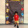 Josiah joined the competition — help win amazing prizes! apple, black_shoes, boy, chalkboard, child, clock, curly_hair, floor, globe, illustrations, indoor, paint_palette, portrait, red_shirt, school_backdrop, scissors, standing, toddler, wall, yellow_shorts