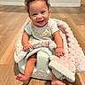 baby, child, smiling, curly_hair, blanket, baby_seat, floor, wooden_floor, indoors, happy, cute, infant, sitting, clothing, portrait, face, person, cozy, toddler, home