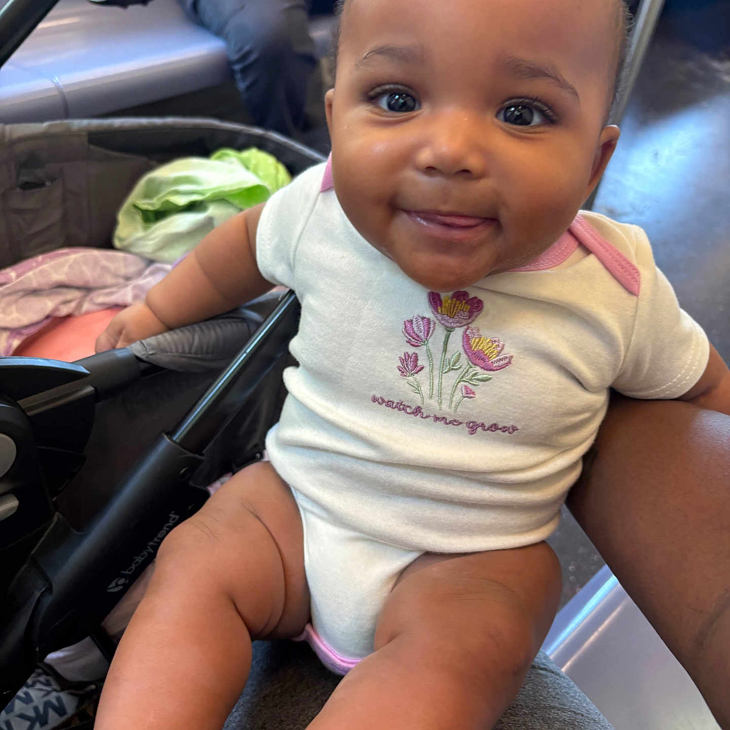 Mckenna joined the competition — help win amazing prizes! baby, child, onesie, smiling, tongue_out, stroller, person, indoor, seat, legs, arm, fabric, clothing, cute, happy, face, head, skin, eyes, casual
