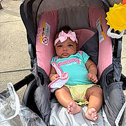 Mckenna joined the competition — help win amazing prizes! baby, blanket, child, clothing, cute, expressionless, fire_hydrant, footwearless, headband, infant, outdoor, person, pink_bow, seat, sidewalk, sitting, stroller, sun_toy, toddler, toy