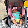 baby, blanket, child, clothing, cute, expressionless, fire_hydrant, footwearless, headband, infant, outdoor, person, pink_bow, seat, sidewalk, sitting, stroller, sun_toy, toddler, toy