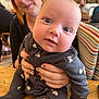 baby, background, blue_eyes, cafe, child, clothing, face, hands, holding, indoor, nails, pattern, person, red_hair, seat, smile, striped, table, woman, wood