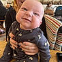Jac is registered to the contest to win money with this photo: baby, blanket, café, child, cute, expression, face, furniture, happy, holding, indoor, nails, onesie, patterned_clothing, person, smiling, striped_blanket, table, woman, wooden_table