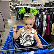 Samuel is registered to the contest to win money with this photo: toddler, child, shopping_cart, green_headband, striped_tank_top, denim_shorts, blue_eyes, indoor, clothing_racks, goodwill, store, retail, aisle, smiling, cute, person, happy, playful, headwear, baby