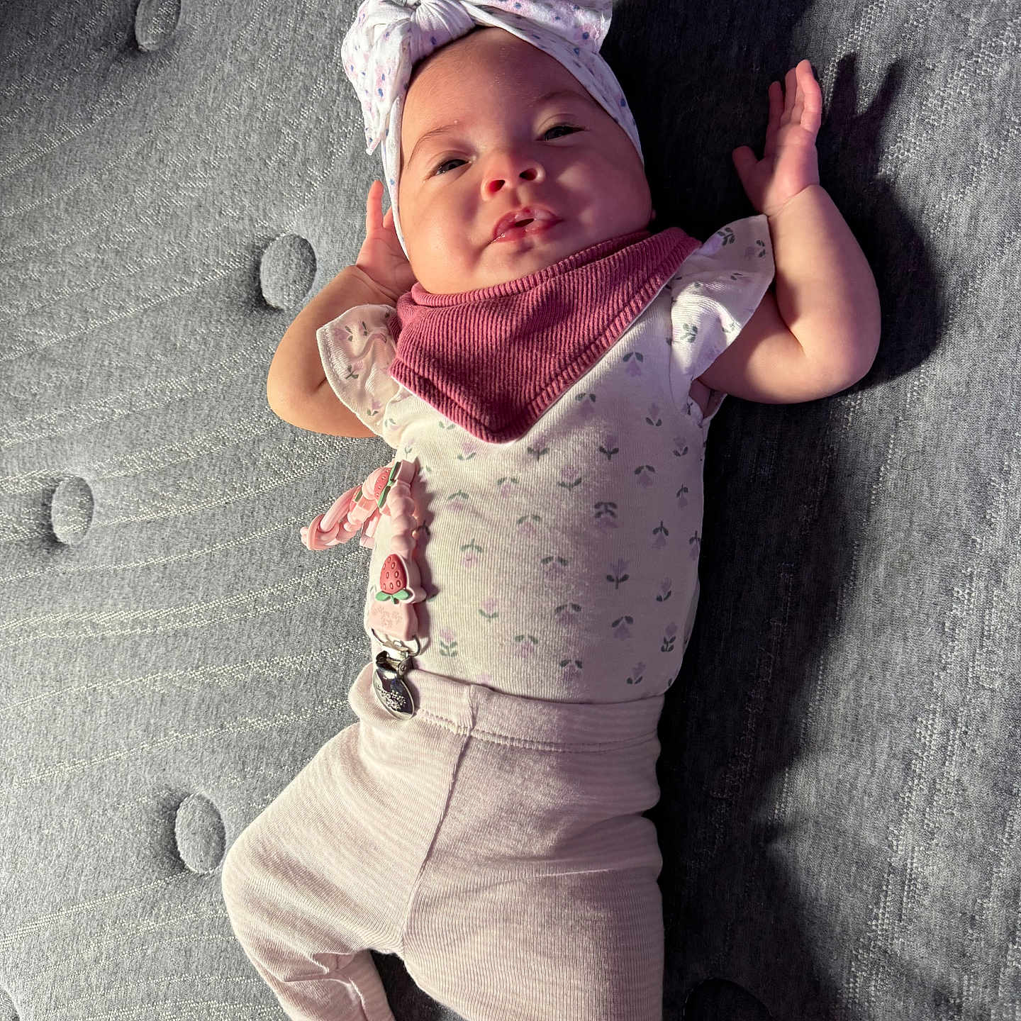Amari is registered to the contest to win money with this photo: arms, baby, child, clothing, comfort, cute, expression, fabric, face, gray, headband, indoor, infant, legs, lying_down, person, pink, shadow, soft_light, texture