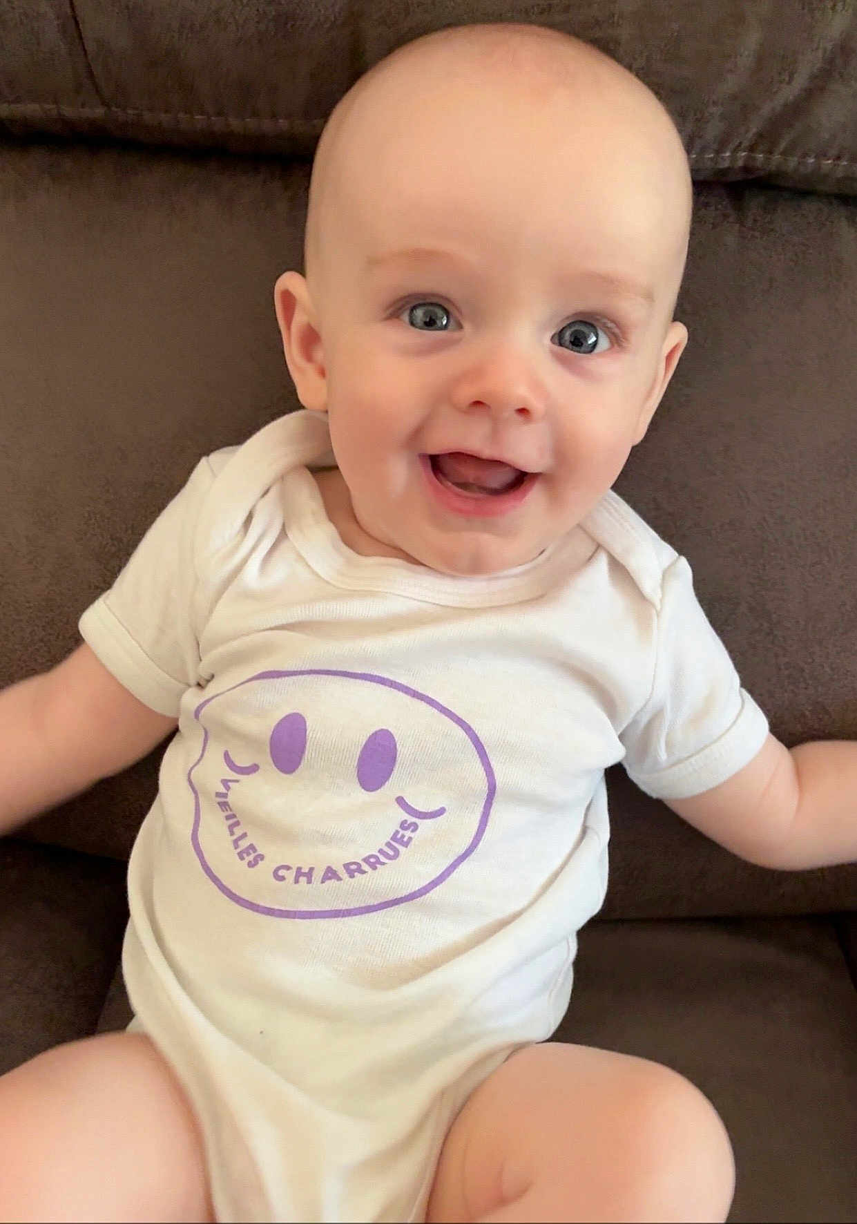 Gabriel a rejoint le concours — aidez-le/la à gagner de superbes lots ! baby, infant, smiling, happy, onesie, white_clothing, purple_print, couch, brown_furniture, seated, portrait, cute, child, face, eyes, head, skin, young, indoors, comfort
