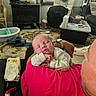 baby, sleeping, adult, shoulder, pink_shirt, indoor, living_room, window, blinds, carpet, furniture, diaper_wipes, bottle, blanket, person, face, head, relaxation, cozy, home