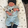 newborn, baby, sleeping, denim_overalls, mickey_mouse, hat, beanie, harley_davidson, socks, star_pattern, blanket, infant, cute, clothing, person, indoor, resting, small_hands, cozy, soft