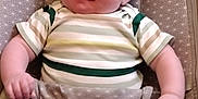 Kayden is registered to the contest to win money with this photo: baby, infant, child, smiling, striped_clothing, onesie, seat, baby_seat, patterned_fabric, chubby_cheeks, cute, relaxed, indoor, portrait, person, human, young, comfort, soft_lighting, happy
