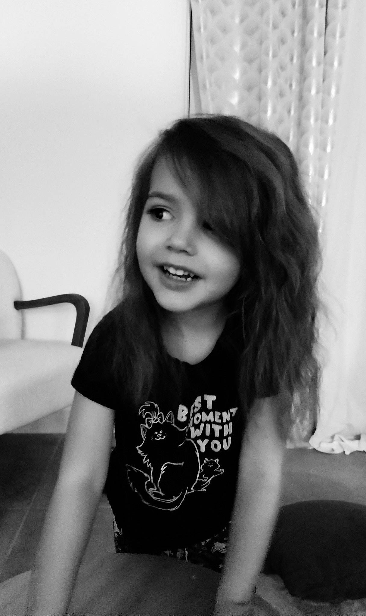 Moïra participe au concours pour gagner de l'argent avec cette photo : black_and_white, black_hair, curtain, eye, eyebrow, flash_photography, hairstyle, happy, human_body, iris, long_hair, monochrome, monochrome_photography, person, sleeve, smile, standing, style, t_shirt, toddler