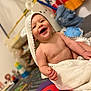 Léo participe au concours pour gagner de l'argent avec cette photo : baby, blanket, child, colorful, cute, happy, hooded_towel, indoor, infant, joyful, person, playmat, playroom, room, sitting, skin, smiling, towel, toy, young_child