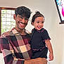 smiling, man, child, glasses, indoor, window, portrait, happy, holding, toddler, black_clothing, bracelet, curly_hair, checkered_shirt, frame, wall, person, family, casual, home