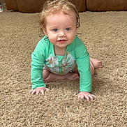Connor joined the competition — help win amazing prizes! toddler, child, baby, crawling, carpet, indoor, living_room, green_clothing, curly_hair, wet_hair, blue_eyes, smiling, brown_couch, home, floor, person, young_child, cute, long_sleeve, playful