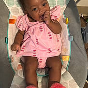 Anari is registered to the contest to win money with this photo: baby, child, infant, pink_dress, watermelon_print, slippers, baby_rocker, indoor, carpet, sitting, thumb_sucking, cute, smiling, happy, person, furniture, footwear, patterned, colorful, comfortable
