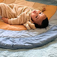 Yasser is registered to the contest to win money with this photo: baby, infant, quilt, blanket, bed, fabric, clothing, soft_texture, child, laying_down, indoor, portrait, cute, warm, relaxed, face, head, eyes, fingers, sleepwear