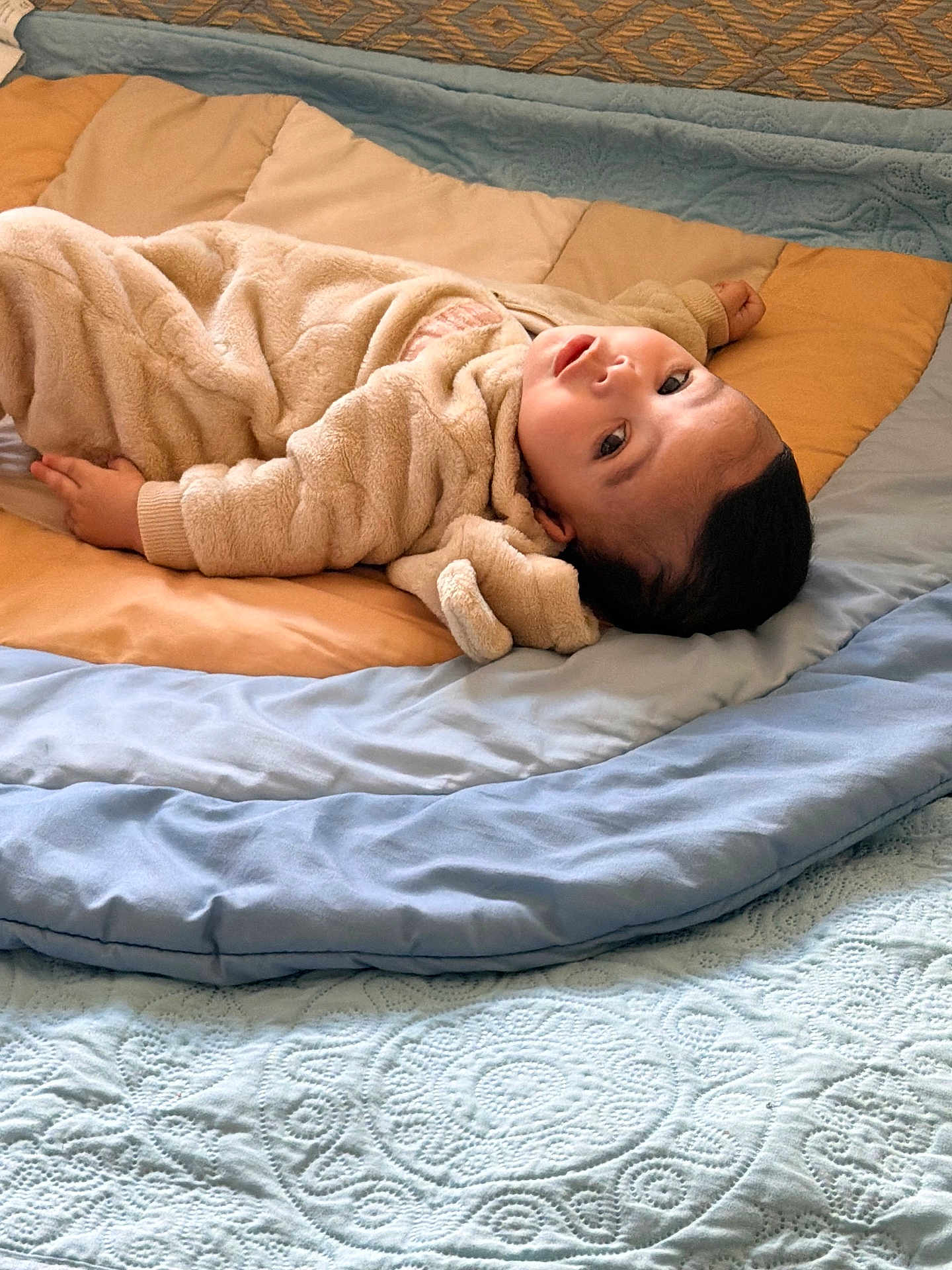 Yasser is registered to the contest to win money with this photo: baby, infant, quilt, blanket, bed, fabric, clothing, soft_texture, child, laying_down, indoor, portrait, cute, warm, relaxed, face, head, eyes, fingers, sleepwear