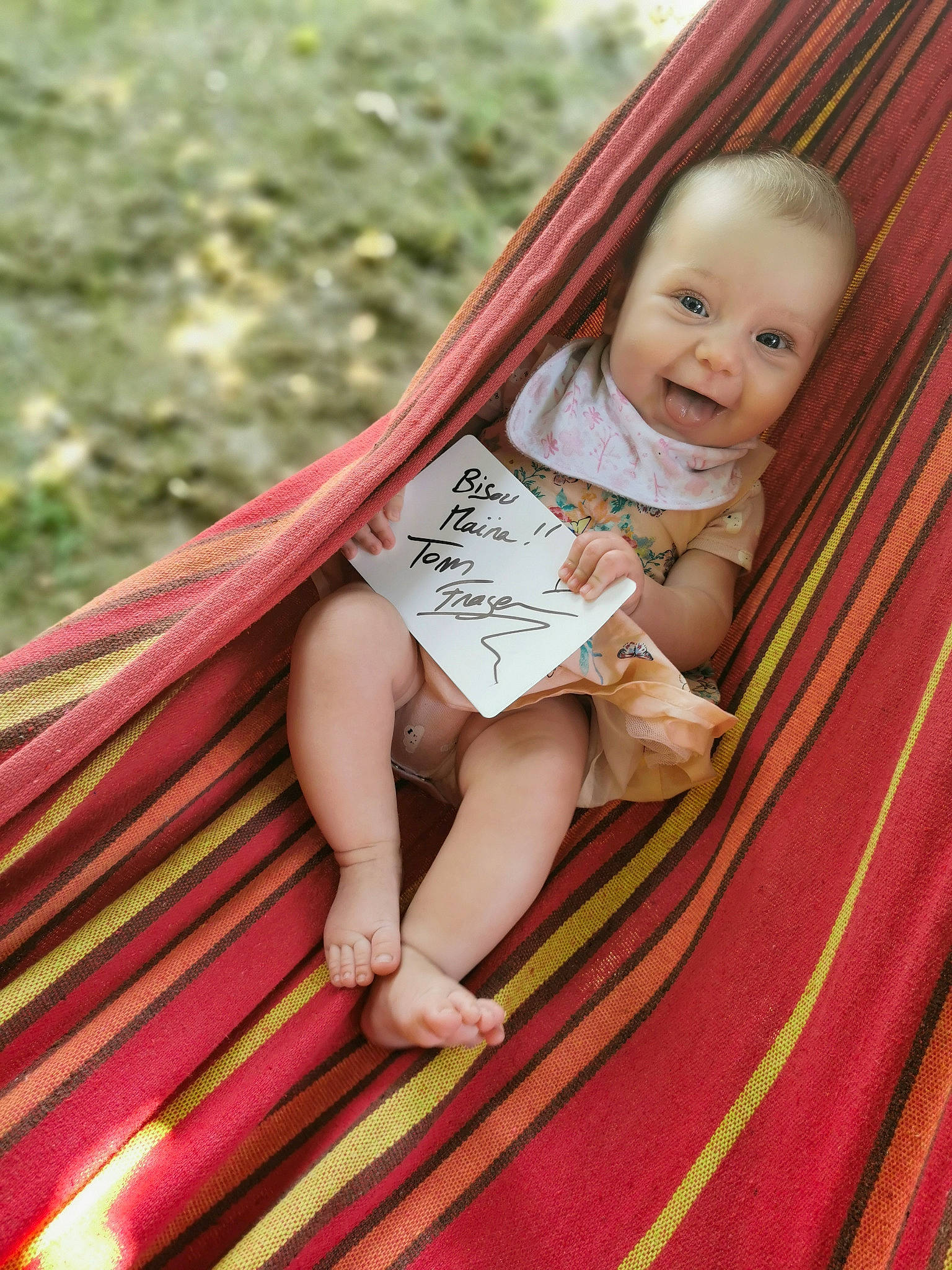 Maïna a rejoint le concours — aidez-le/la à gagner de superbes lots ! arm, baby, baby_toddler_clothing, dress, finger, grass, hand, happy, human_body, leisure, magenta, orange, pattern, people_in_nature, person, pink, red, skin, textile, toddler