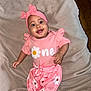 baby, child, smiling, pink_clothing, headband, daisy_pattern, blanket, happy, infant, cute, portrait, indoors, one_year_old, toddler, young_child, fashion, soft_texture, lying_down, person, adorable