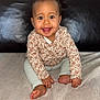 baby, child, smiling, sitting, happy, face, person, indoor, blanket, couch, leather, clothing, long_sleeve, pants, feet, hand, cute, portrait, infant, young