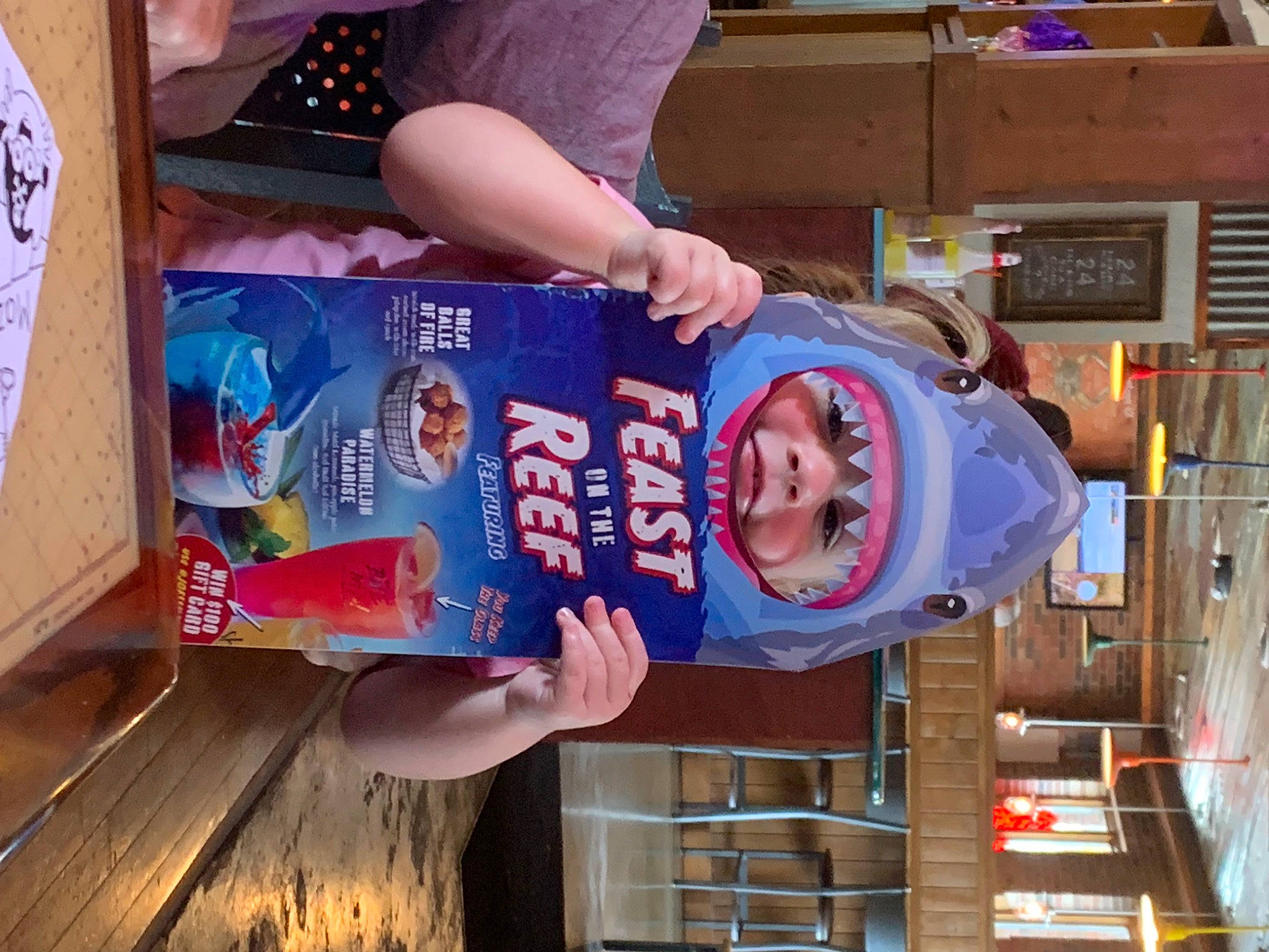 Addilynn is registered to the contest to win money with this photo: child, electric_blue, food, fun, hat, headwear, person, publication, t_shirt, toddler, wood