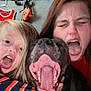 black_dog, casual, child, closeup, dog, facial_expression, family, fishing_rod, fun, hanger, happy, indoor, long_hair, person, playful, red_shirt, striped_shirt, tank_top, tongue_out, yawning_dog