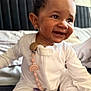 baby, child, smile, curly_hair, pajamas, indoor, bedroom, pacifier_clip, rainbow, earring, happy, sitting, face, cute, infant, skin, person, clothing, closeup, portrait