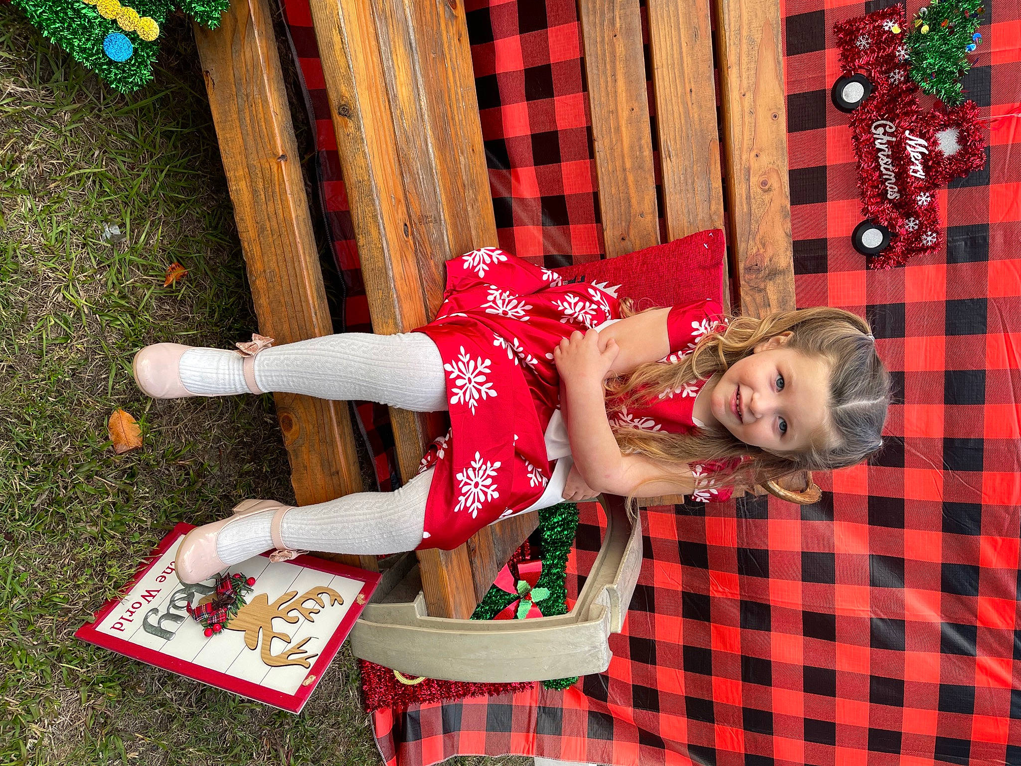 Addilynn is registered to the contest to win money with this photo: baby_toddler_clothing, carmine, child, dress, event, face, fun, grass, green, happy, human_leg, joy, magenta, pattern, person, plaid, red, sandal, smile, tartan