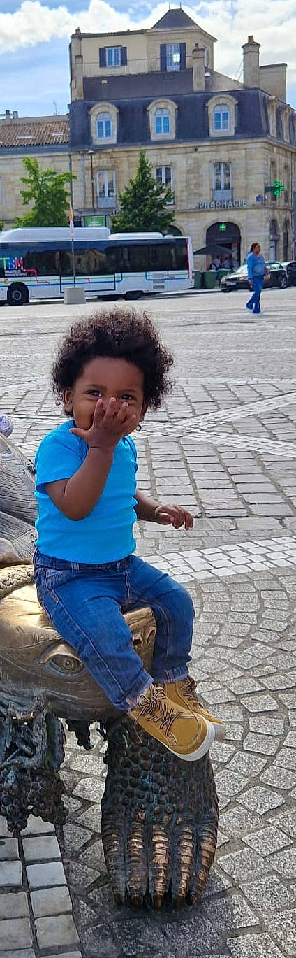 Cyrian a rejoint le concours — aidez-le/la à gagner de superbes lots ! asphalt, blue, child, cool, electric_blue, flooring, fun, happy, human_leg, human_settlement, jeans, leisure, person, play, road, road_surface, sidewalk, sitting, street, toddler