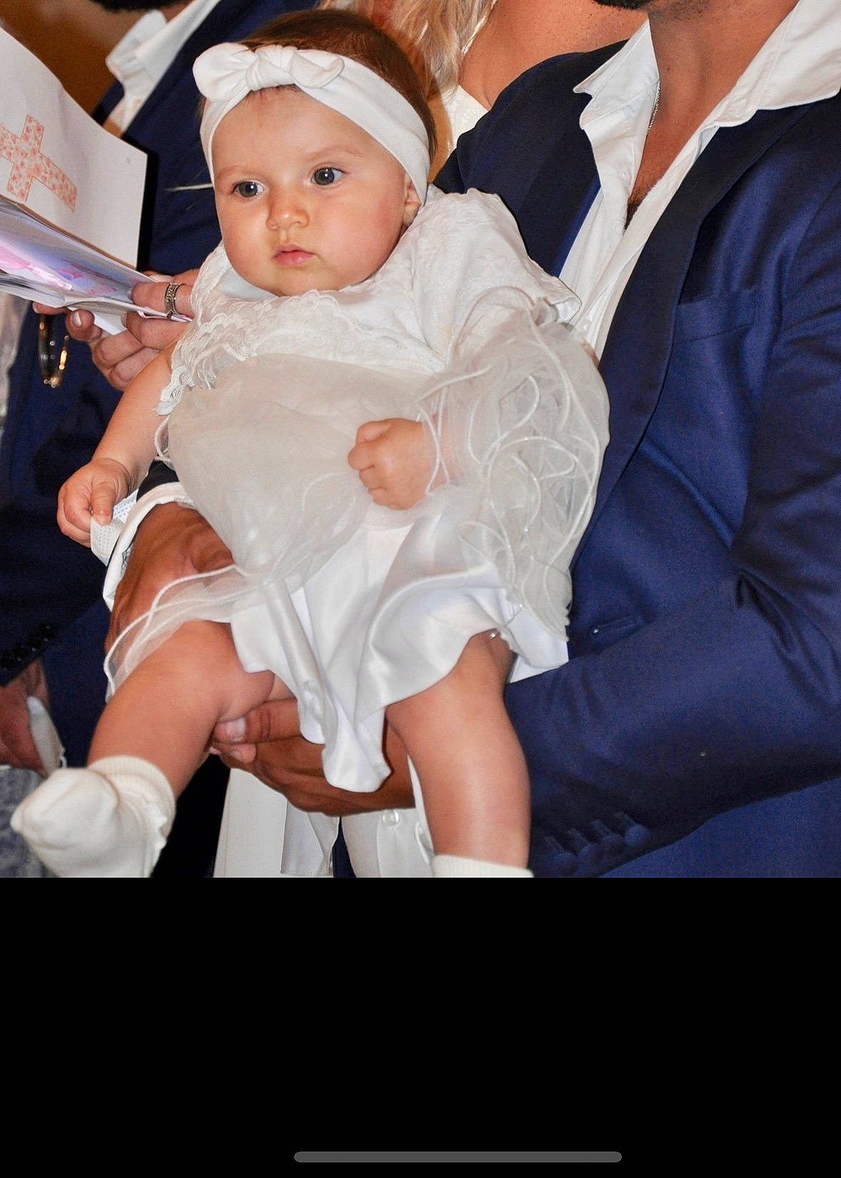 Angelina participe au concours pour gagner de l'argent avec cette photo : baby, baby_toddler_clothing, child, dress, event, eye, fashion, flash_photography, formal_wear, fun, gesture, happy, hat, headpiece, headwear, human, interaction, jewellery, person, sitting