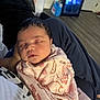 baby, sleeping, blanket, animal_print, indoors, person, lap, cozy, clothing, face, head, resting, comfort, soft, cute, infant, human, young_child, peaceful, relaxation