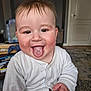 Theo is registered to the contest to win money with this photo: baby, child, tongue_out, white_onesie, indoor, smiling, happy, face, hand, hair, clock, furniture, carpet, door, room, person, cute, playful, skin, expression