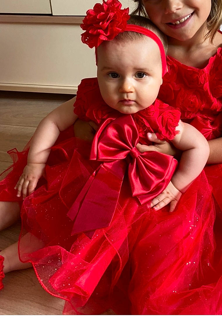 Alaïys participe au concours pour gagner de l'argent avec cette photo : baby, child, child_model, clothing, costume, dress, gown, hair_accessory, headband, joy, magenta, person, petal, pink, red, satin, smile, textile, toddler