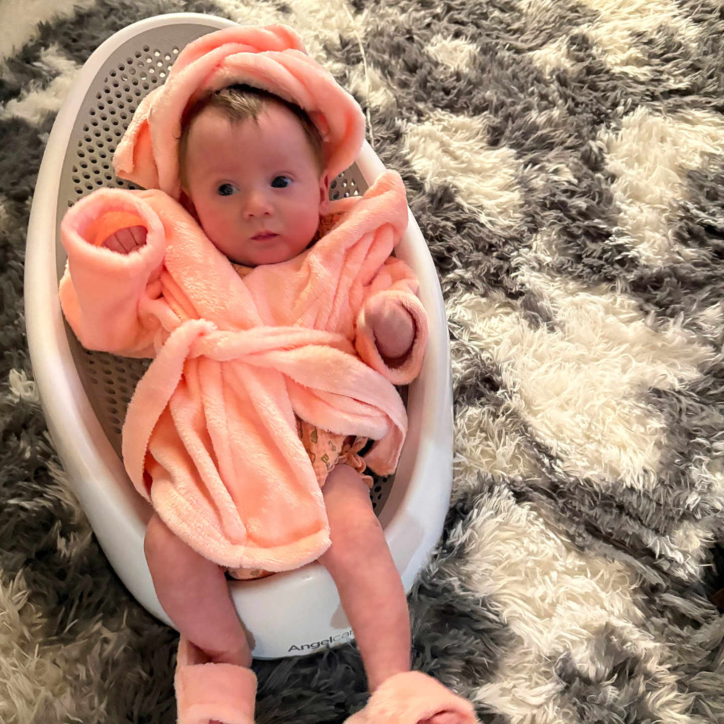 Melodie joined the competition — help win amazing prizes! baby, infant, robe, bath_seat, footwear, fluffy, soft_texture, carpet, indoor, child, cute, pink, white, gray, sitting, portrait, cozy, warm, person, home