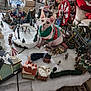 animal, cat, christmas_tree, decorations, ferris_wheel, festive, figurines, hairless_cat, holiday_decor, ice_skaters, indoor, living_room, miniature_village, pillow, snow, sofa, sweater, table, toys, winter_scene